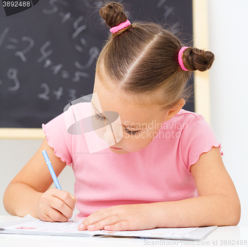 Image of Little girl is writing using a pen