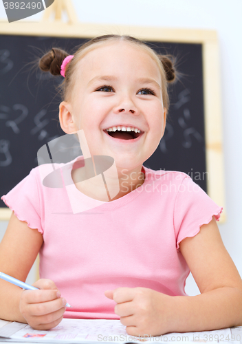 Image of Little girl is writing using a pen