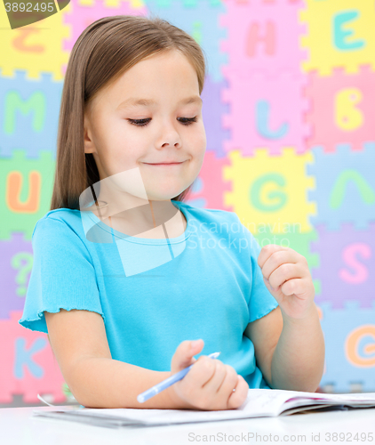 Image of Little girl is writing using a pen