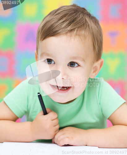 Image of Little girl is writing using a pen