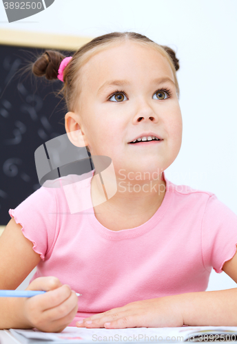 Image of Little girl is writing using a pen