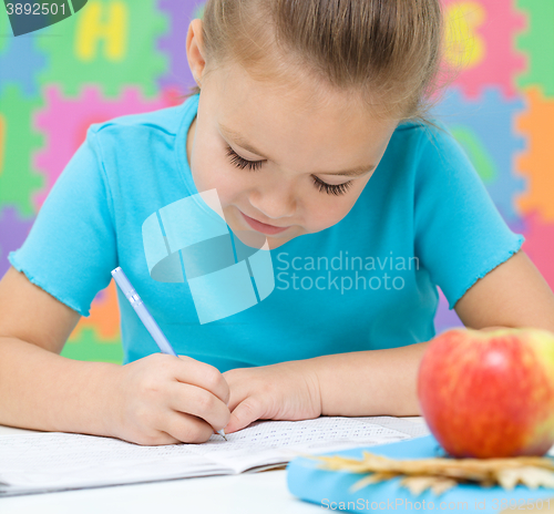 Image of Little girl is writing using a pen