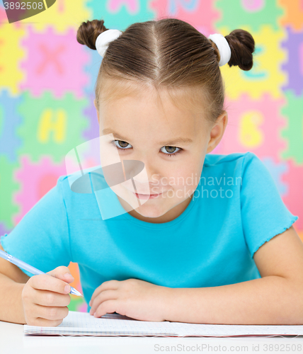 Image of Little girl is writing using a pen