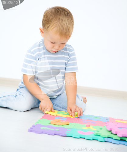 Image of Little boy is putting together a big puzzle