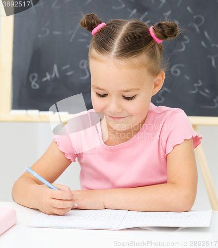 Image of Little girl is writing using a pen