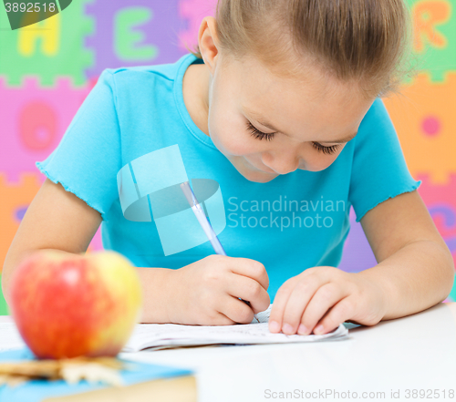 Image of Little girl is writing using a pen