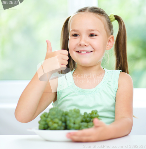Image of Cute little girl is eating green grapes