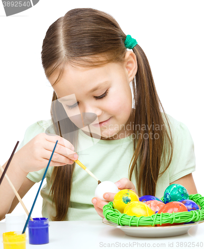 Image of Little girl is painting eggs preparing for Easter