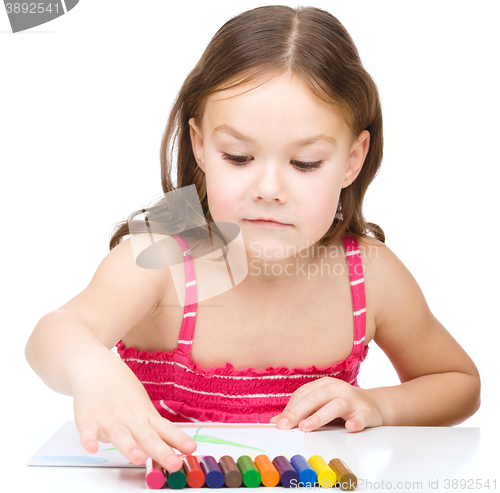 Image of Little girl is drawing using colorful crayons