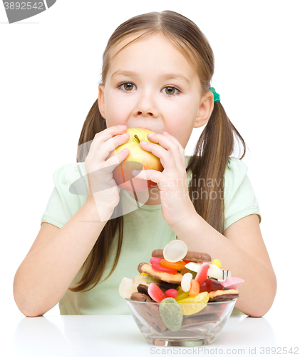 Image of Little girl choosing between apples and sweets