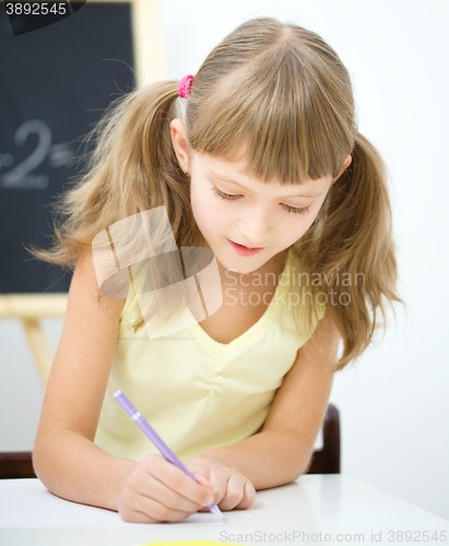 Image of Little girl is writing using a pen