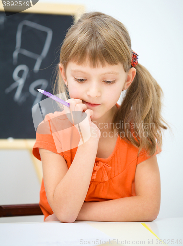 Image of Little girl is writing using a pen