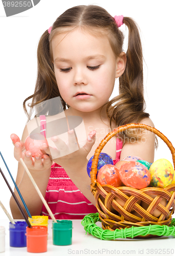 Image of Little girl is painting eggs preparing for Easter