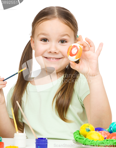 Image of Little girl is painting eggs preparing for Easter