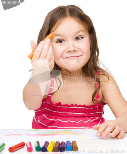 Image of Little girl is drawing using colorful crayons