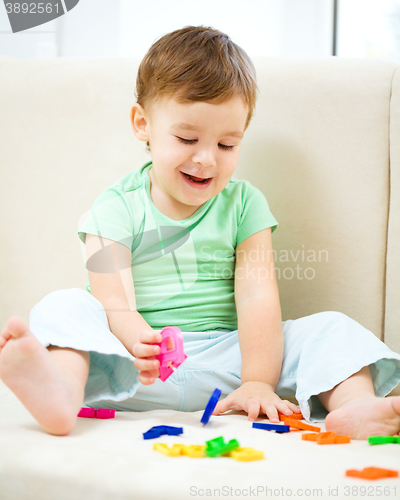 Image of Boy is playing while sitting on couch