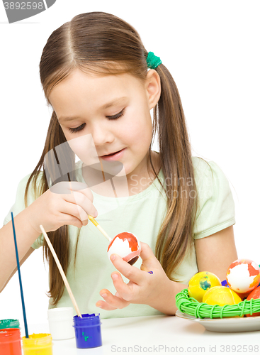 Image of Little girl is painting eggs preparing for Easter