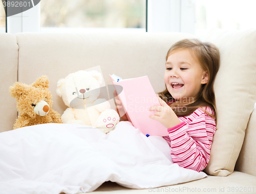 Image of Little girl is reading a story for her teddy bears