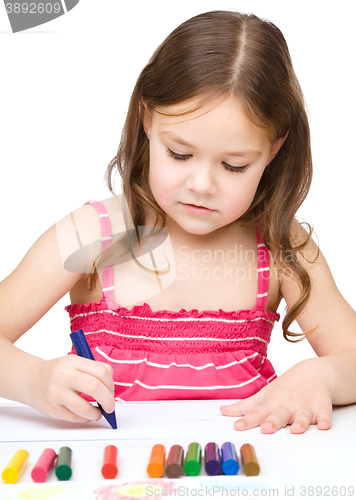Image of Little girl is drawing using a crayon