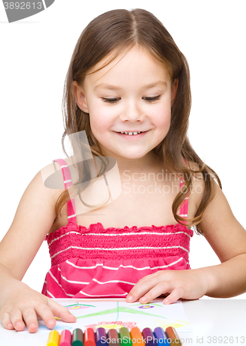 Image of Little girl is drawing using colorful crayons