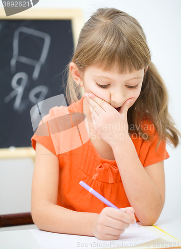 Image of Little girl is writing using a pen