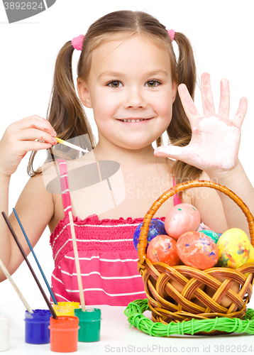 Image of Little girl is painting eggs preparing for Easter