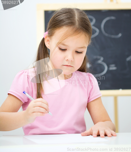 Image of Little girl is writing using a pen