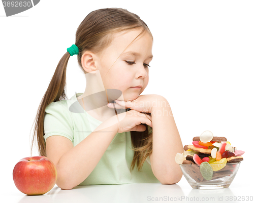 Image of Little girl choosing between apples and sweets