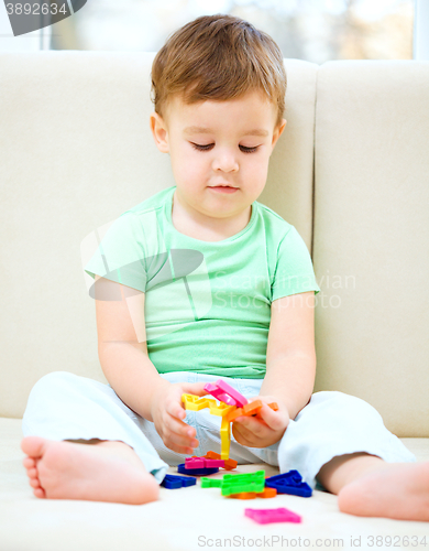 Image of Boy is playing while sitting on couch
