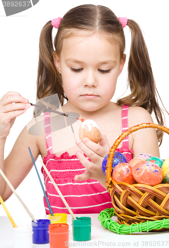 Image of Little girl is painting eggs preparing for Easter