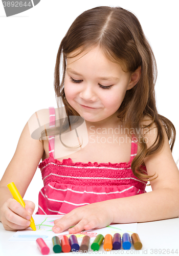 Image of Little girl is drawing using colorful crayons