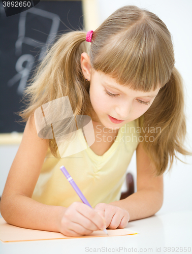 Image of Little girl is writing using a pen