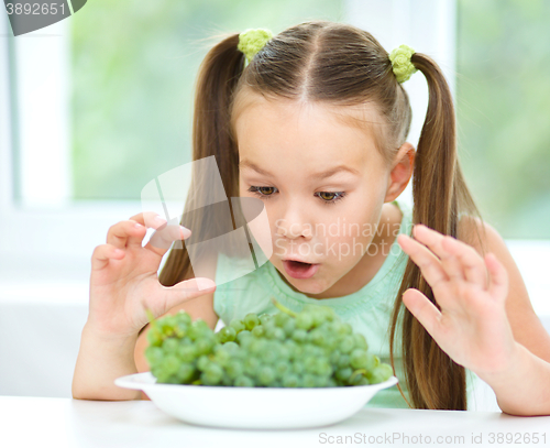 Image of Cute little girl is eating green grapes