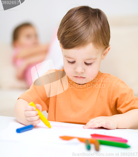 Image of Little boy is drawing on white paper