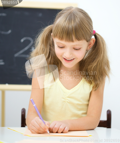 Image of Little girl is writing using a pen