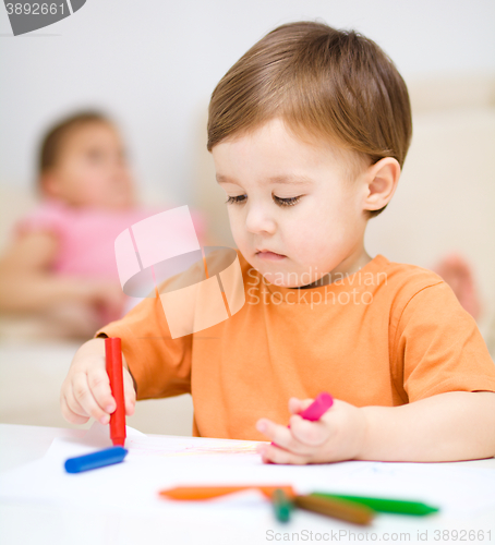 Image of Little boy is drawing on white paper