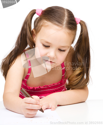 Image of Little girl is drawing using a crayon