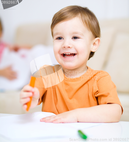 Image of Little boy is drawing on white paper