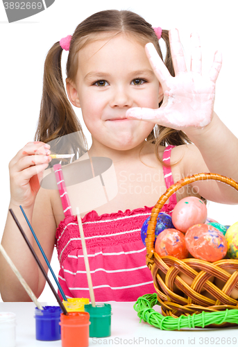 Image of Little girl is painting eggs preparing for Easter
