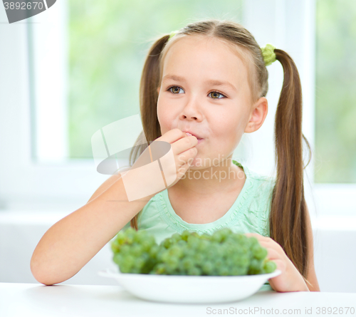 Image of Cute little girl is eating green grapes