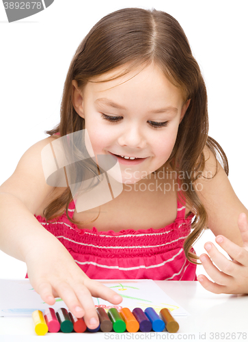 Image of Little girl is drawing using colorful crayons