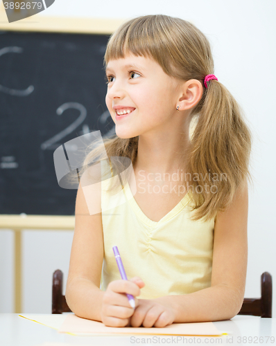 Image of Little girl is writing using a pen