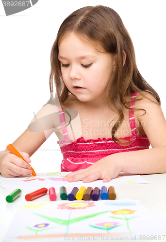 Image of Little girl is drawing using a crayon