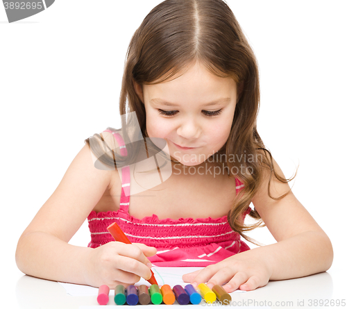 Image of Little girl is drawing using colorful crayons