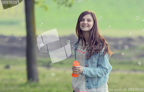 Image of Young girl play with soap-bubbles