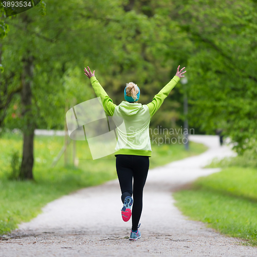Image of Sporty young female runner in city park.