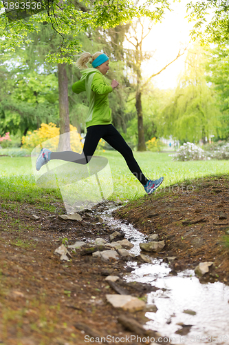 Image of Sporty young female runner in city park. 