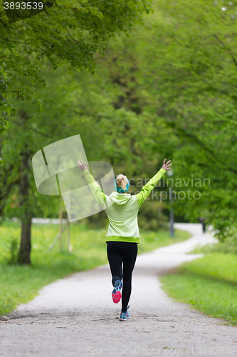 Image of Sporty young female runner in city park.