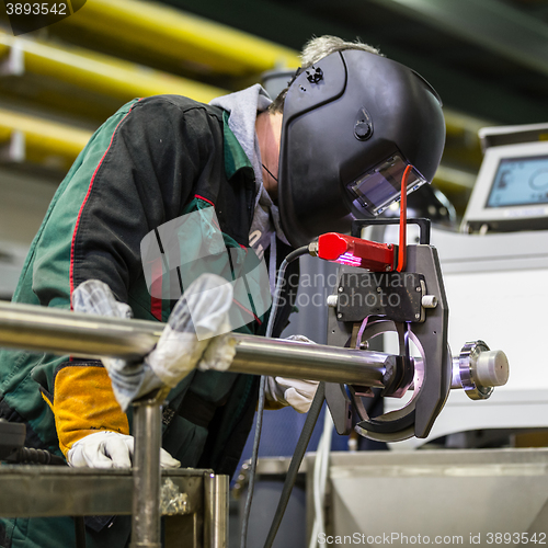 Image of Industrial worker setting orbital welding machine.