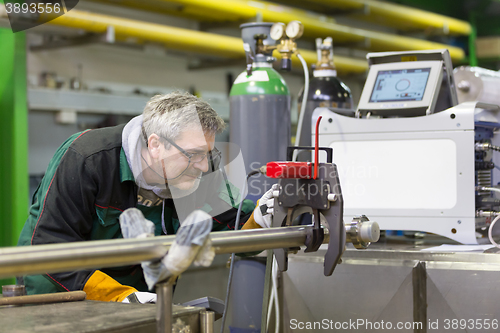 Image of Industrial worker setting orbital welding machine.